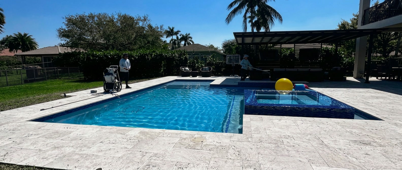 Pool King technicians servicing a travertine deck pool in Broward County